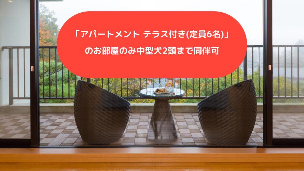 una señal en una ventana con mesa y sillas en スイートヴィラ 箱根強羅, en Gora