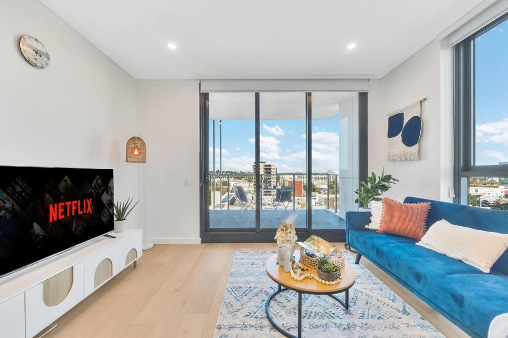 sala de estar con sofá azul y TV en Vivid home in Bankstown 2B2B, en Bankstown