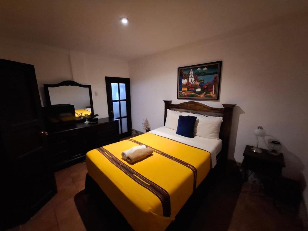 ein Schlafzimmer mit einem gelben Bett und einem Spiegel in der Unterkunft Casa Santiago Son in Antigua Guatemala