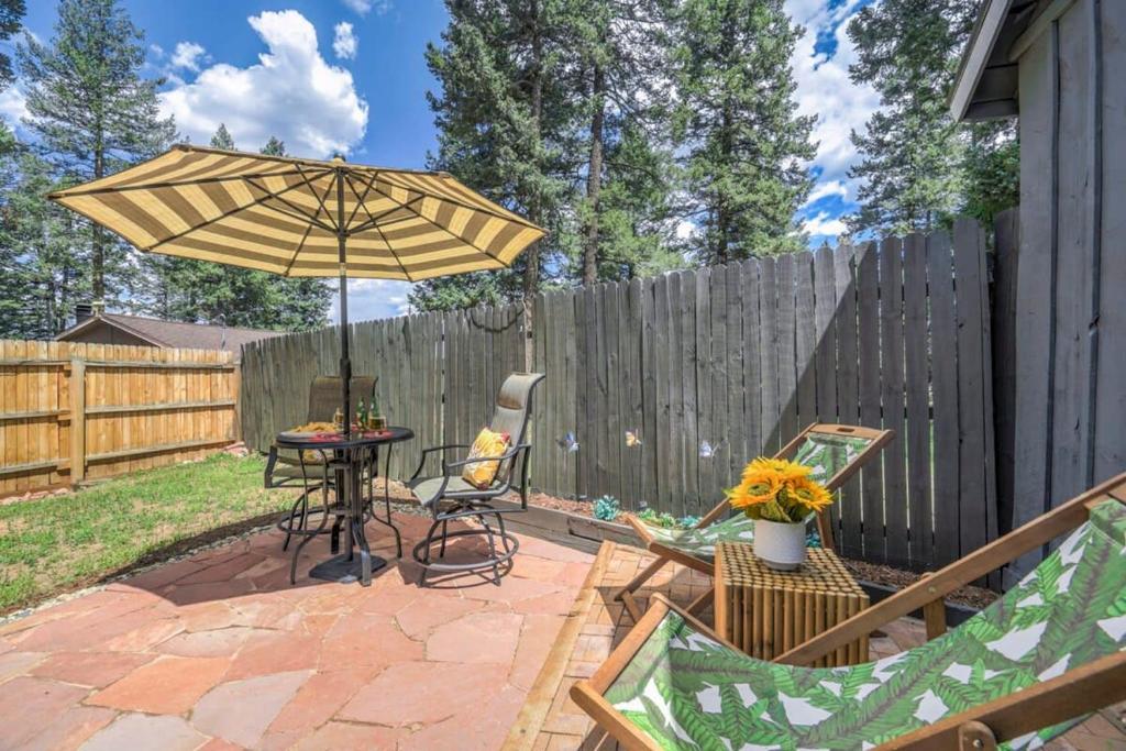 a patio with an umbrella and a table and chairs at 1BR Woodland Hideaway - Downtown and Hiking Nearby in Woodland Park