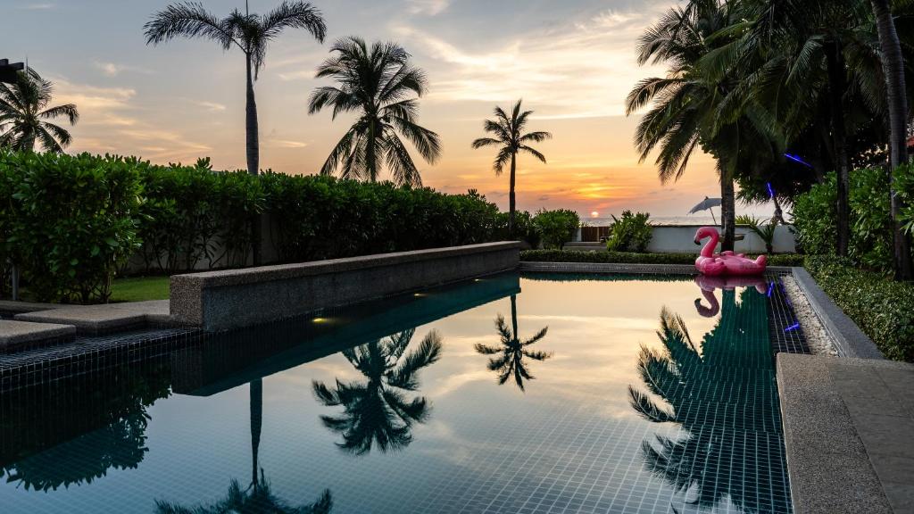 a pool with a pink flamingo and palm trees at AP Natai Luxury Beachfront Pool Villas in Phang-nga