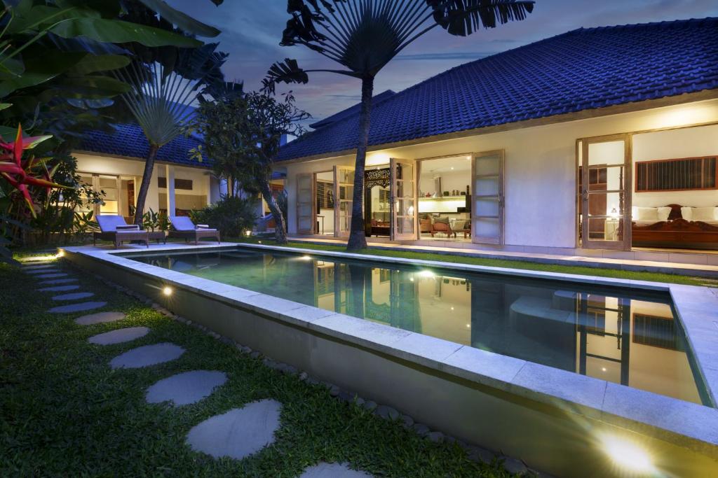 una piscina infinita en el patio trasero de una casa por la noche en Villa Puri Pura, en Canggu