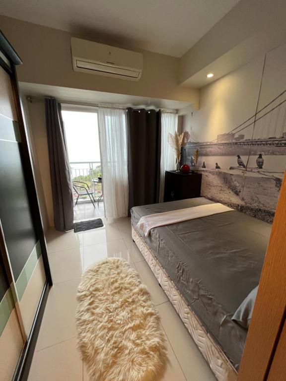 Schlafzimmer mit einem Bett, einem Fenster und einem Teppich in der Unterkunft SMDC FORT TAGAYTAY STAYCATION in Kaybagal