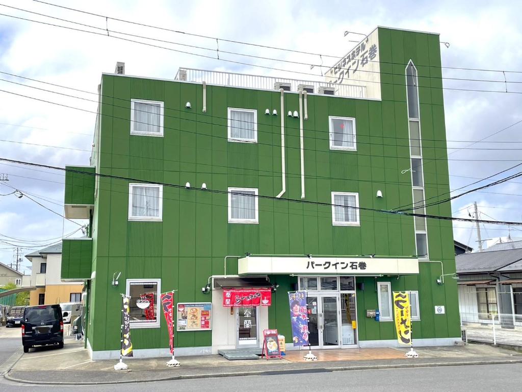 a green building on the corner of a street at ビジネスホテルパークイン石巻 in Inai