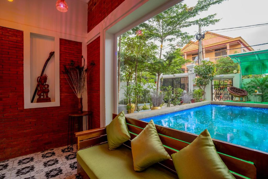 Phumĭ Ta PhŭlにあるAngkor Rithy Residenceのソファと窓付きの客室内のスイミングプールを利用できます。