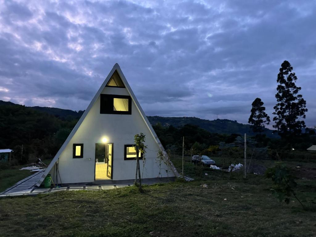 ein kleines Haus mit einem dreieckigen Dach auf einem Feld in der Unterkunft Ilusion Cabins La Florida in Pereira