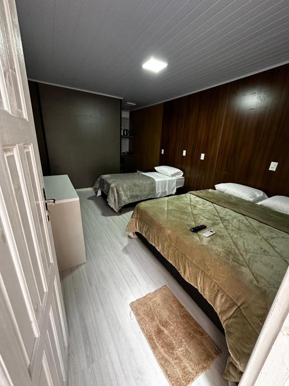 a bedroom with two beds and a door with a rug at Loft Lux 7 in Chapecó