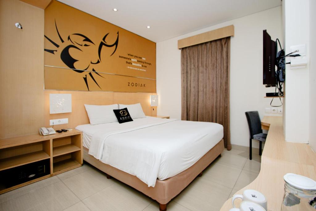 Zodiak Asia Afrika by KAGUM Hotels في باندونغ: غرفة فندق بسرير وتلفزيون