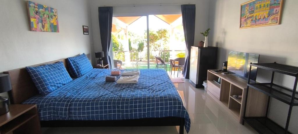 een slaapkamer met een blauw bed en een televisie bij Yawee & Jo Guesthouse in Ban Phe