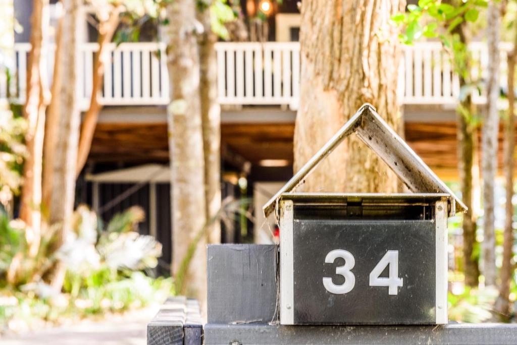 a house with the number in front of a tree at Treetops in Pearl Beach