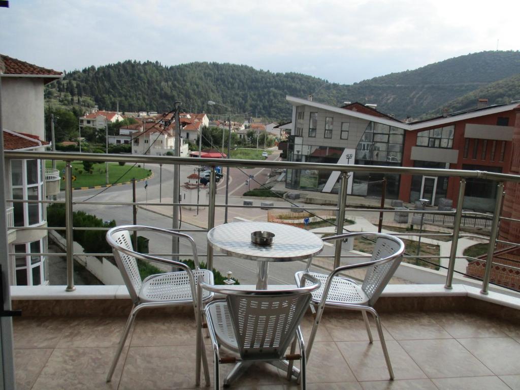 patio con mesa y sillas en el balcón en Kyknos De Luxe Suites & Rooms, en Kastoria