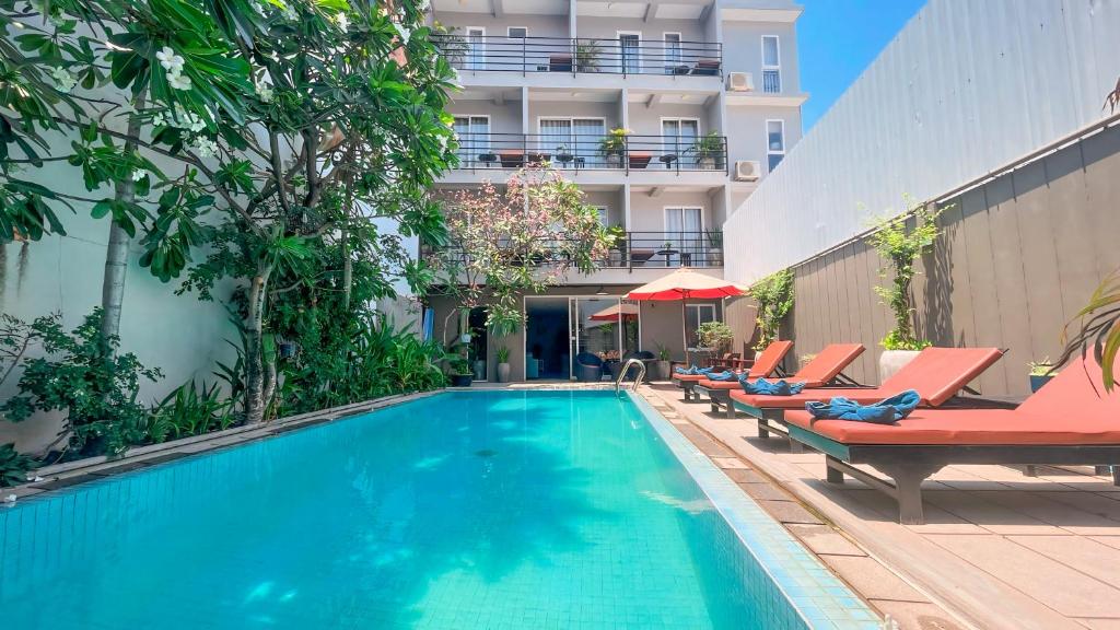 een zwembad met ligstoelen en een gebouw bij Dusit Hotel Siem Reap in Siem Reap