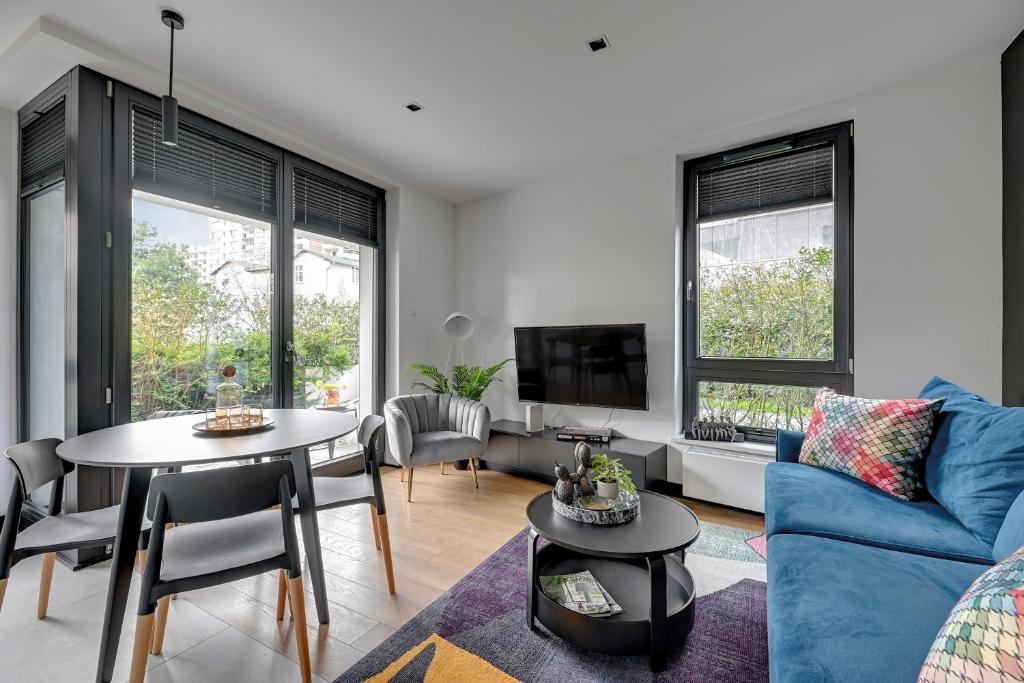 uma sala de estar com um sofá azul e uma mesa em Lion Apartments - Sopot Fresh Wave Apartment with terrace and parking em Sopot