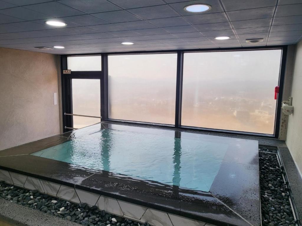 a swimming pool in a room with large windows at WJ Hotel Pool House in Wonju
