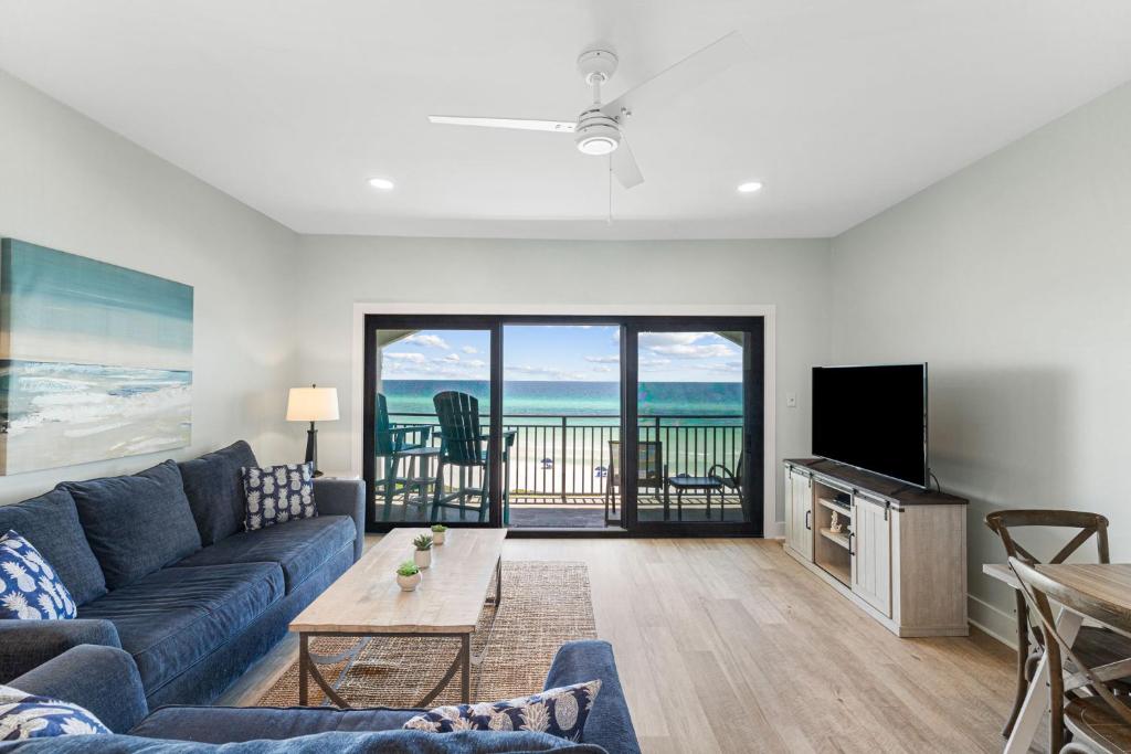 sala de estar con sofá azul y TV en Palms of Seagrove C13 - Gulf Front, Bikes, Pool Sleeps 6, en Seagrove Beach