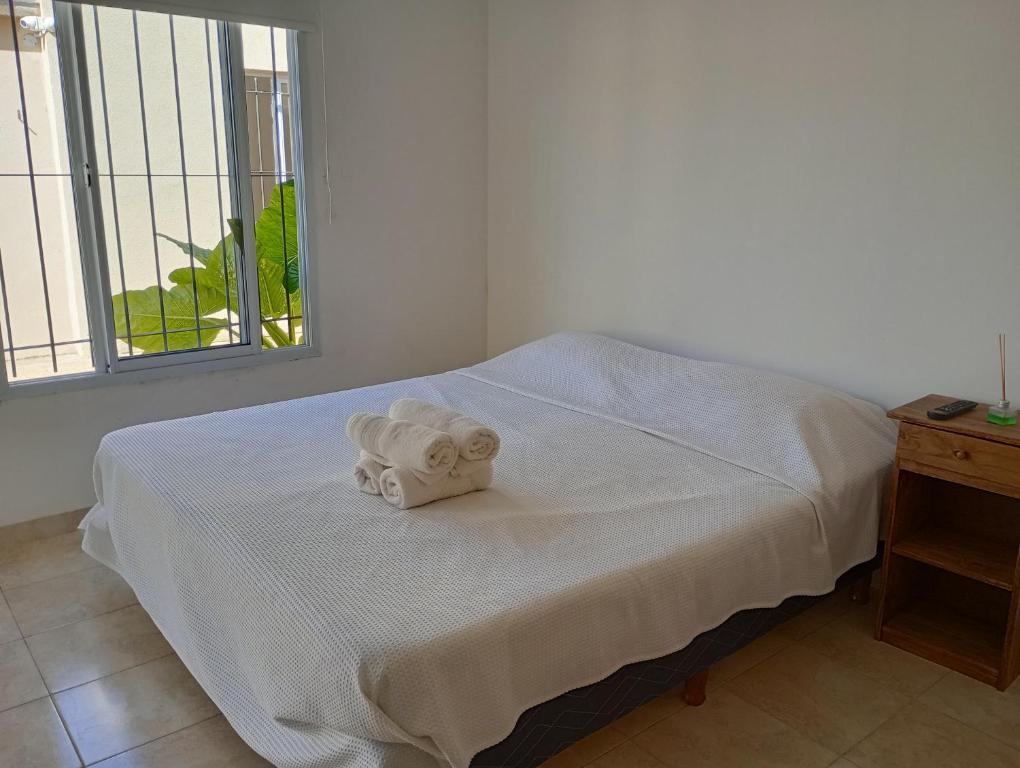Una cama blanca con una toalla encima. en Posada la Península en Gualeguaychú