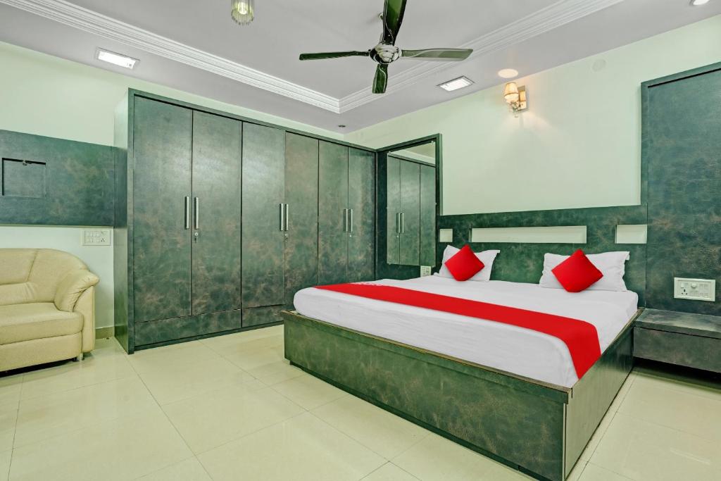 a bedroom with a bed with red pillows and a chair at Flagship Hotel Pragya 4 in Raipur