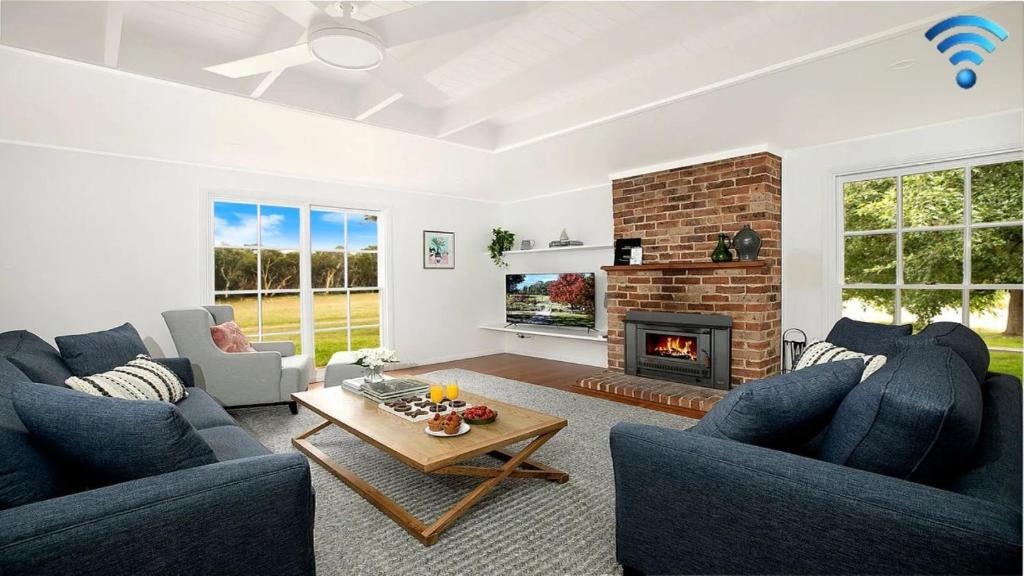 a living room with two blue couches and a fireplace at Whisky Creek in Berrima