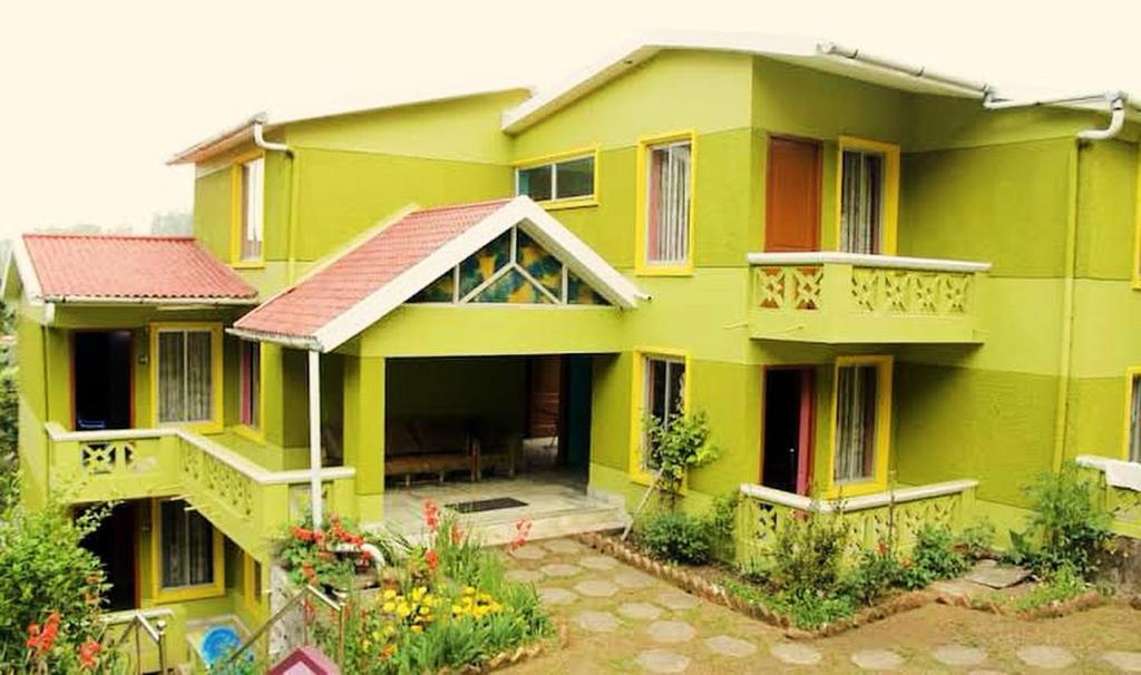 科代卡那的住宿－Mookambigai Residency，一座大型绿色房子,设有阳台和鲜花