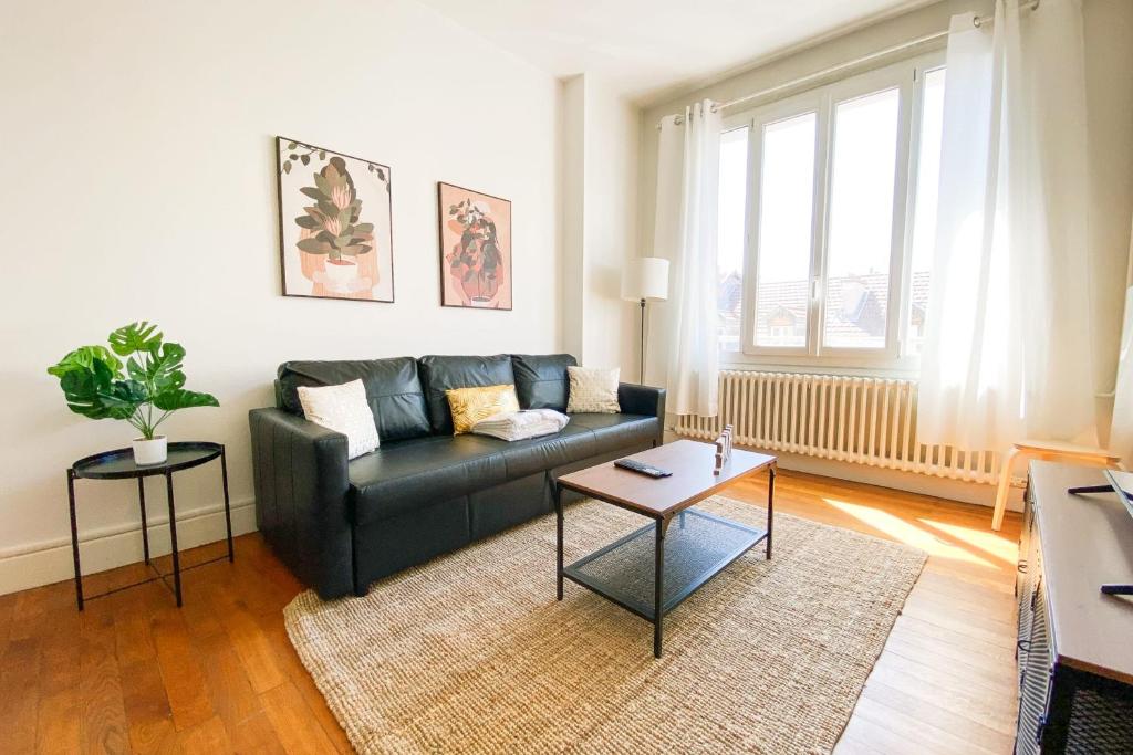 un salon avec un canapé noir et une table dans l'établissement #GP The Berri'Appart, à Grenoble