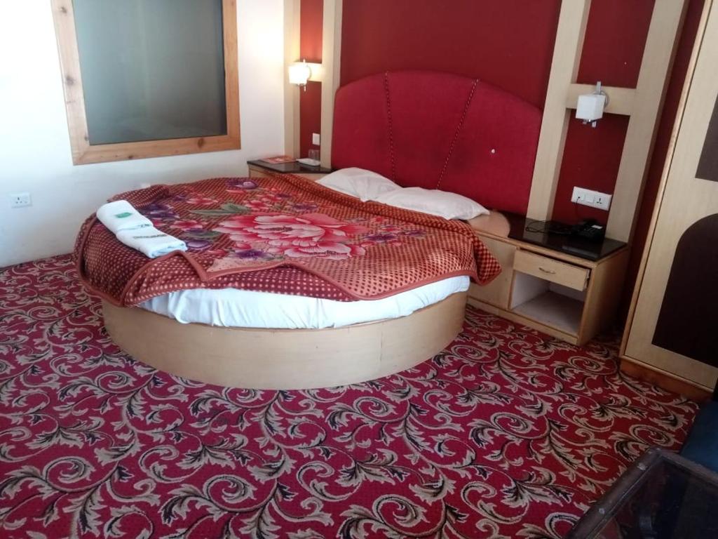 a bedroom with a large bed with a red headboard at kamal seawa sadan manali in Manāli