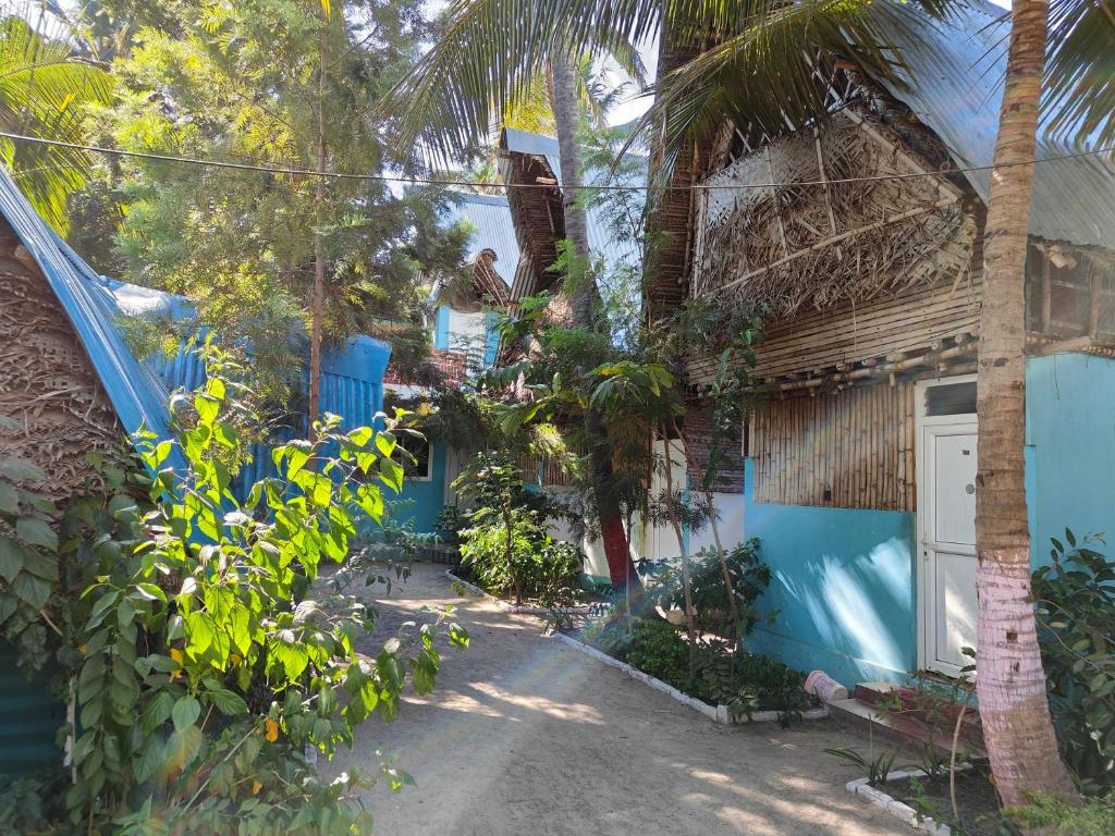 a house with a palm tree next to a driveway at Saikani Beach Resort & Eco stay in Virāmpattinam