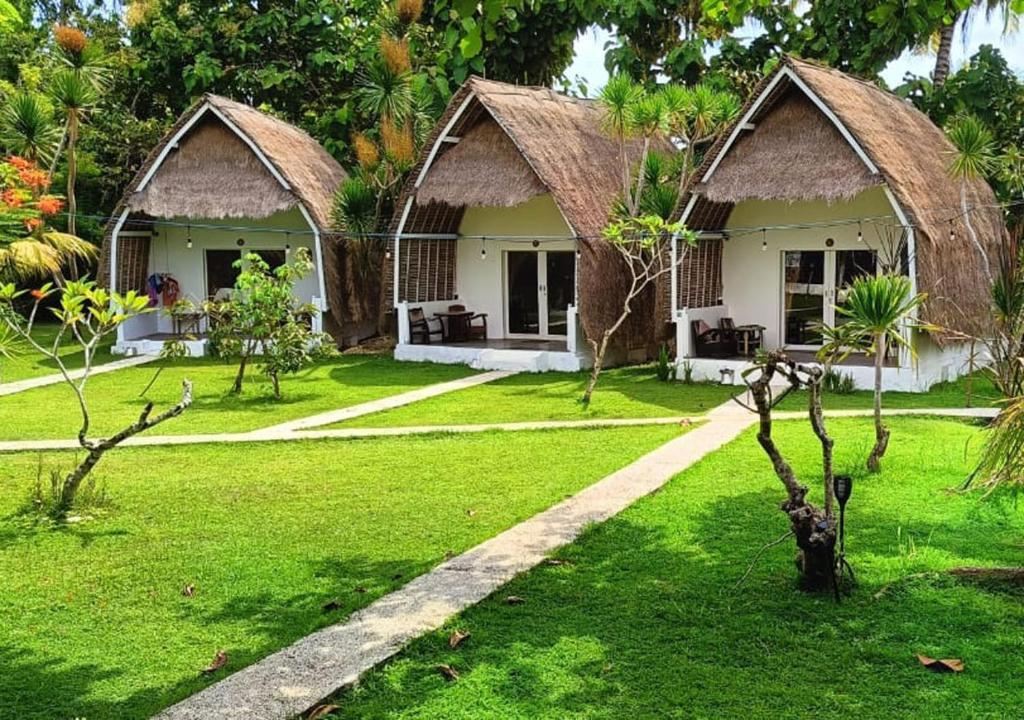 un complejo con 2 casas de campo en un patio verde en Namaste Bungalows, en Nusa Penida