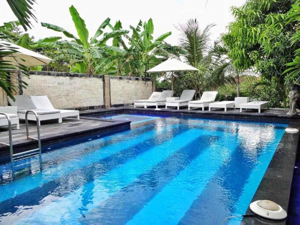 una piscina con sedie a sdraio bianche e un piscina con piscina di Villa Cempaka Lembongan a Nusa Lembongan