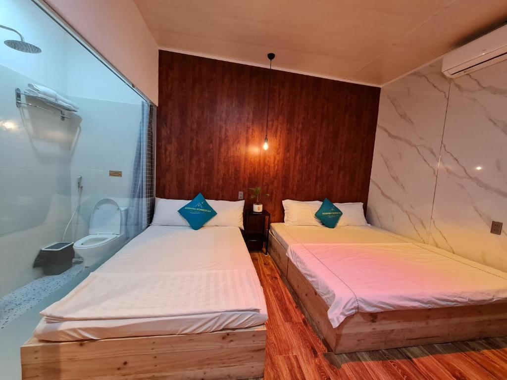 two twin beds in a room with a bathroom at Banana homestay( Chuối Homestay) in Hue