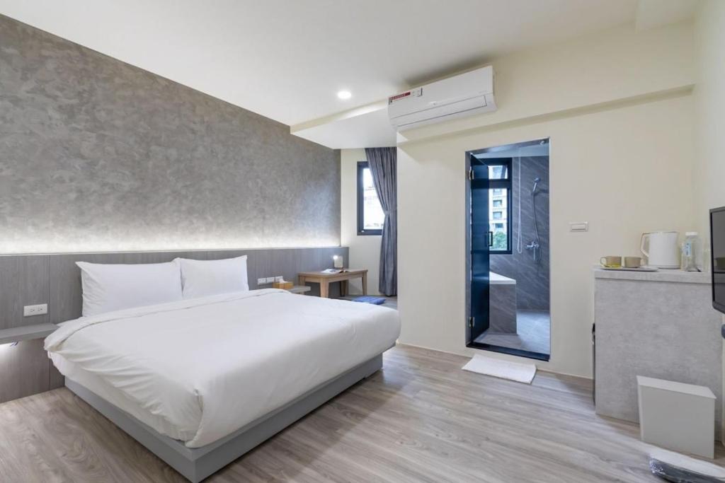 a bedroom with a white bed and a kitchen at 礁溪亞都溫泉旅店 Newly Renovated in Jiaoxi