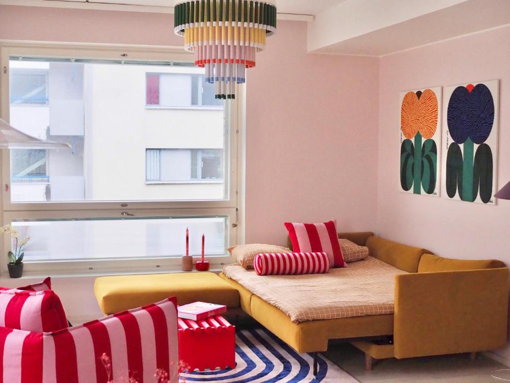 a living room with a couch and a window at Candy-Colored Two-Room Condo with Sweet views in Helsinki