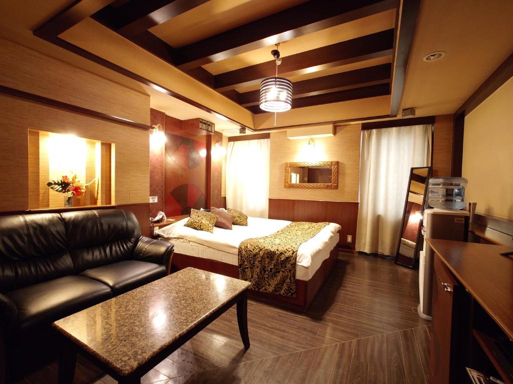 a hotel room with a bed and a couch at ホテル カーシュ Cache 男塾ホテルグループ in Himeji