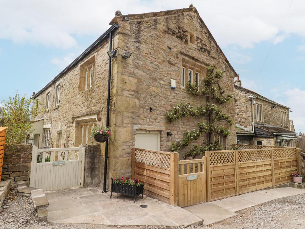 uma casa de pedra com uma cerca de madeira em frente em Pear Tree Cottage at Hey Farm em Barnoldswick