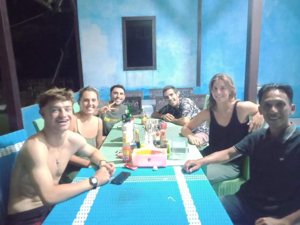 um grupo de pessoas sentadas à volta de uma mesa com um bolo em Karang Besi Losmen em Biha