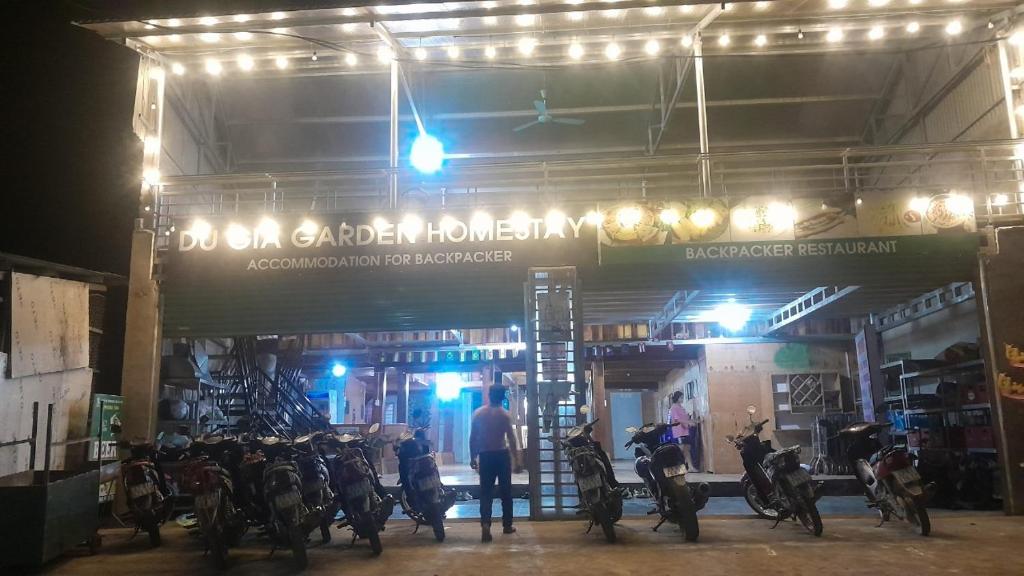 Làng Cac的住宿－Bungalow Du Gia，一名男子在夜间站在摩托车商店前