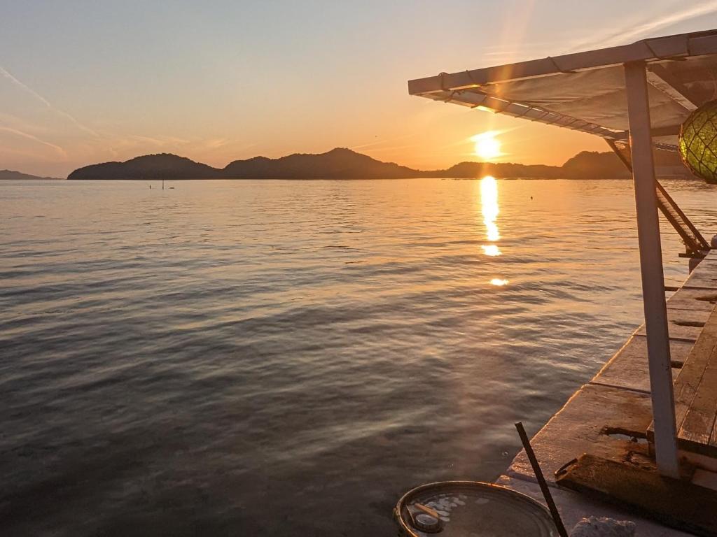 宇和島市にある千代丸コンテナハウスの夕日を背景に水中の船