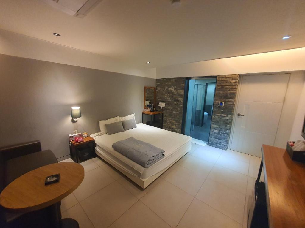 um quarto com uma cama, uma mesa e uma casa de banho em Yeonsan Oops Hotel em Busan