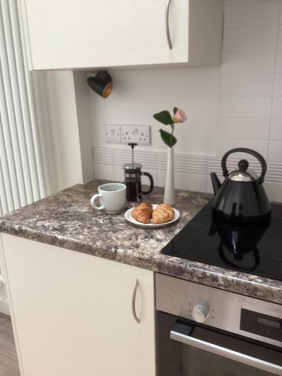 a kitchen counter with a plate of croissants and a tea kettle at Forest Heath Holidays - The Nook in Ringwood