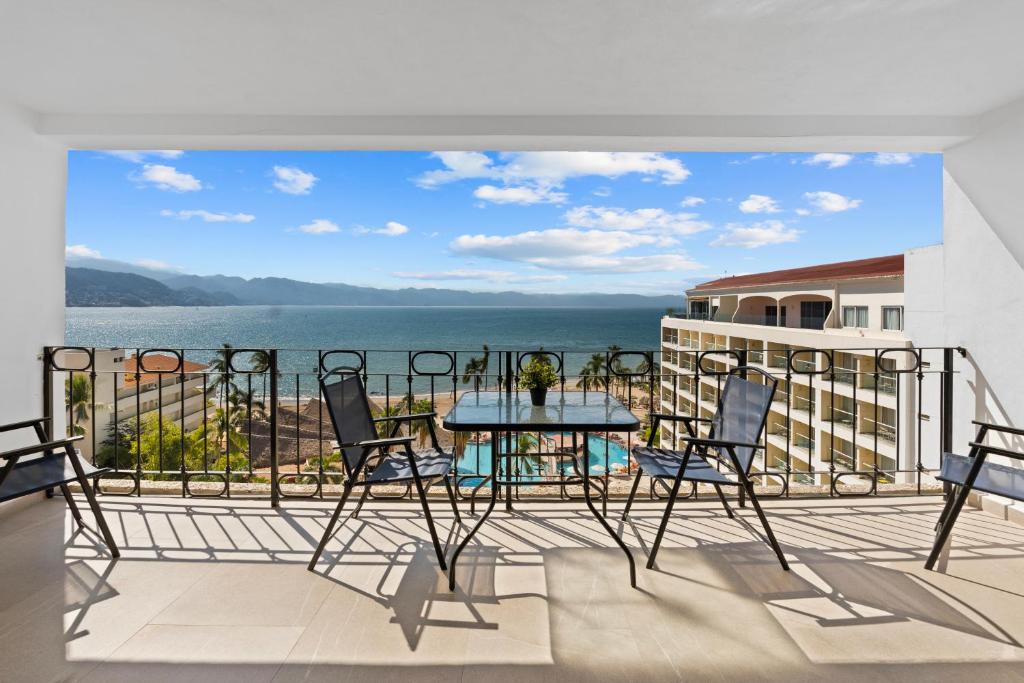 a balcony with a table and chairs and a view of the water at Luxury Condo just steps away from the Beach! in Puerto Vallarta