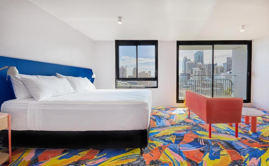 Adge Hotel and Residence - Adge King - Australia في سيدني: غرفة نوم بسرير كبير وكرسي احمر