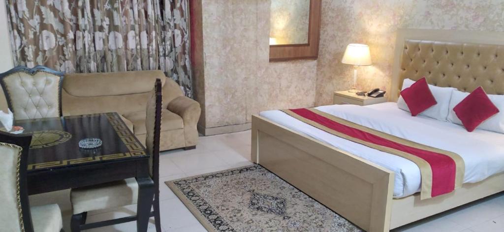 a bedroom with a bed and a table and a chair at Premier Inn Davis Road Lahore in Lahore