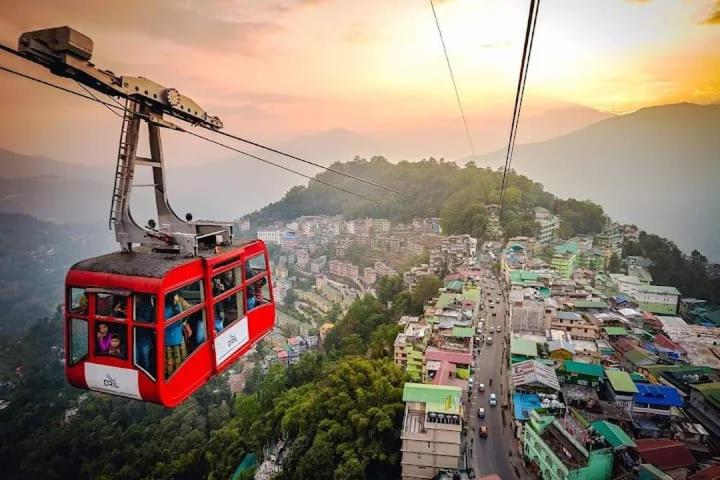 a red cable car flying over a city at dup in Shillong