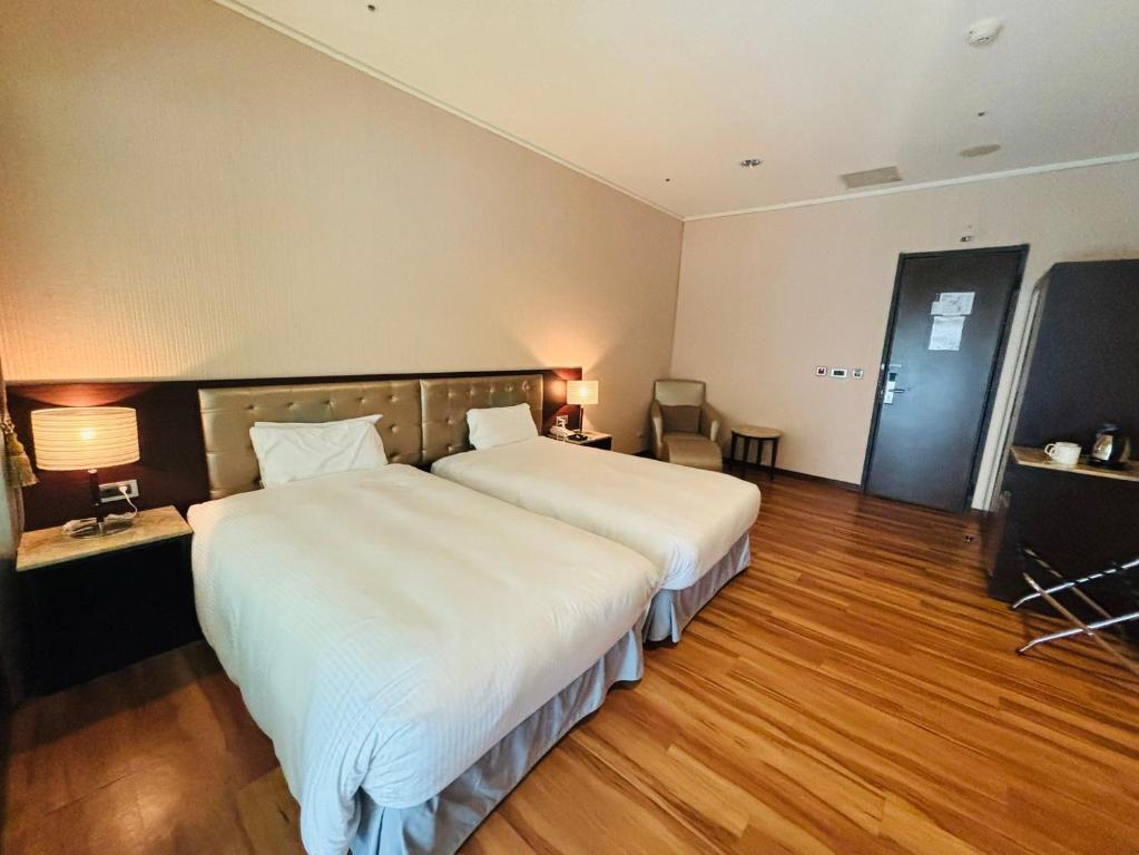 a large bedroom with a large white bed and wooden floors at New Taipei Hot Spring Hotel in Xindian