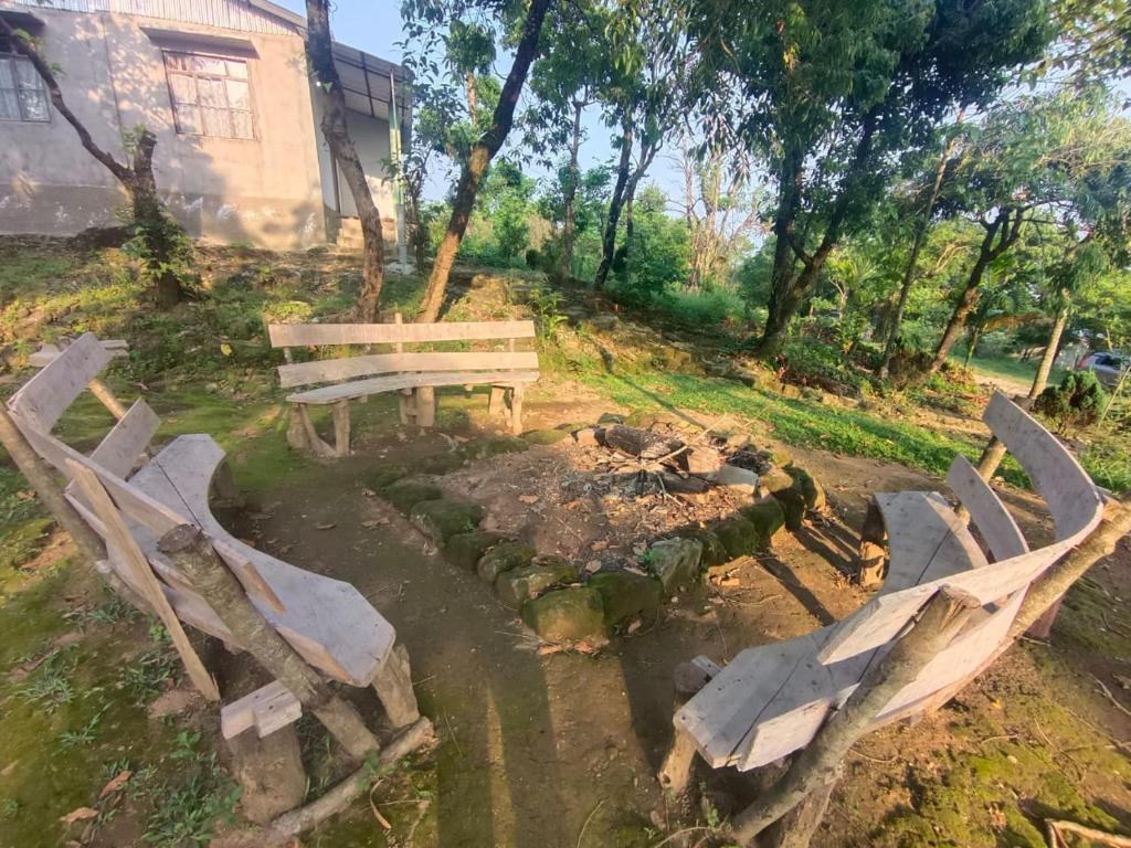 un banc en bois assis dans une cour à côté d'un feu dans l'établissement Ibankordor Jungle Resort, à Cherrapunji
