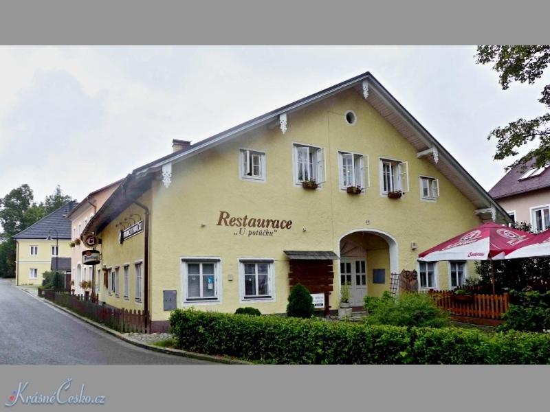 a large yellow building with a restaurant on a street at Volarská roubenka in Volary