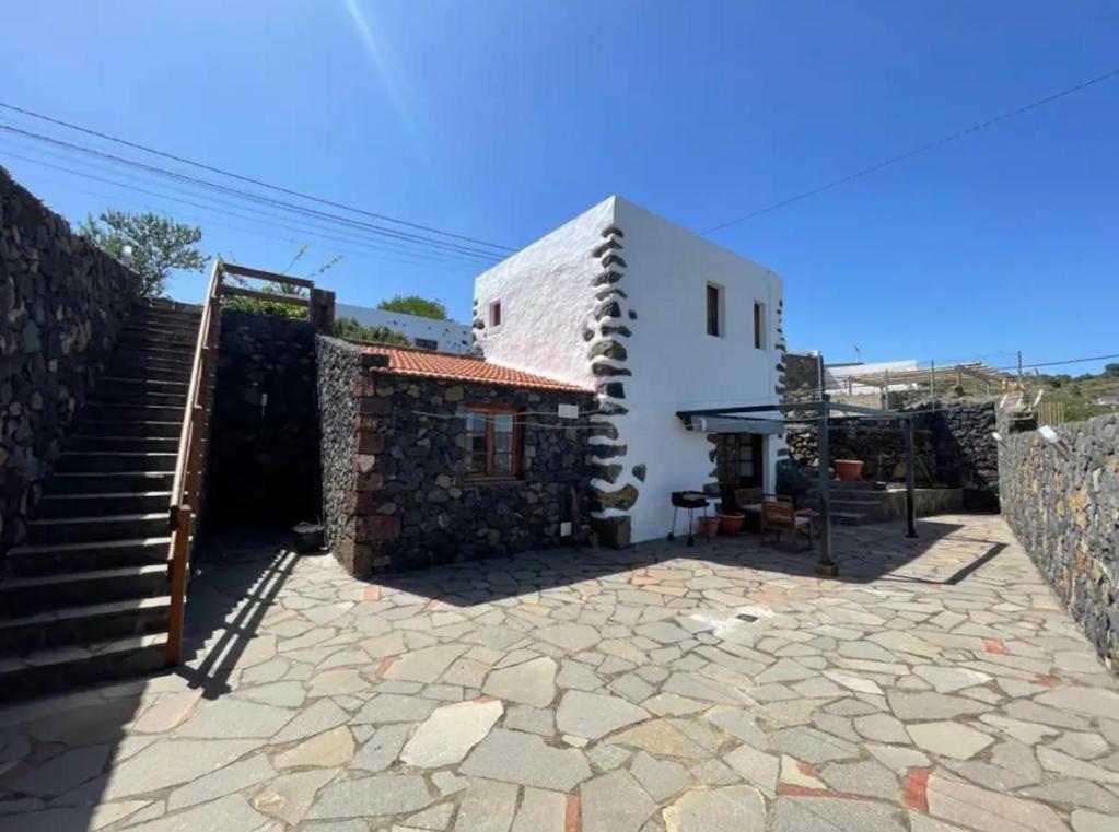 a house with a staircase next to a stone courtyard at Home2Book Charming Casa Nina El Pinar, Terrace in El Pinar del Hierro