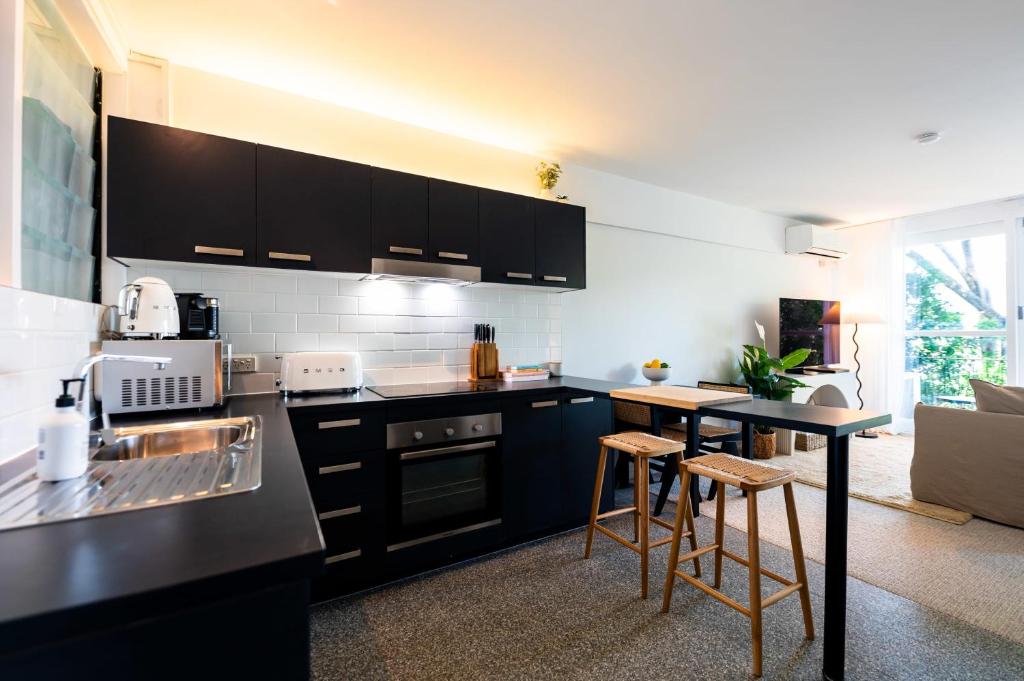 a kitchen with black cabinets and a table with stools at Riverside Studio apartment in Brisbane