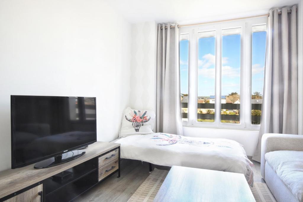un salon blanc avec une télévision et un canapé dans l'établissement En bord de mer - Appt à moins d'un km de la plage, à Barneville-Carteret