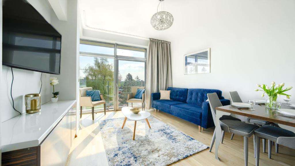 a living room with a blue couch and a table at Apartamenty Sun & Snow Bałtyk Park I in Kołobrzeg