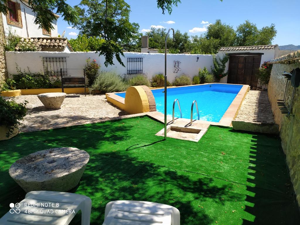 a backyard with a swimming pool with green grass at Cortijo Molino los Justos in Fuentes de Cesna